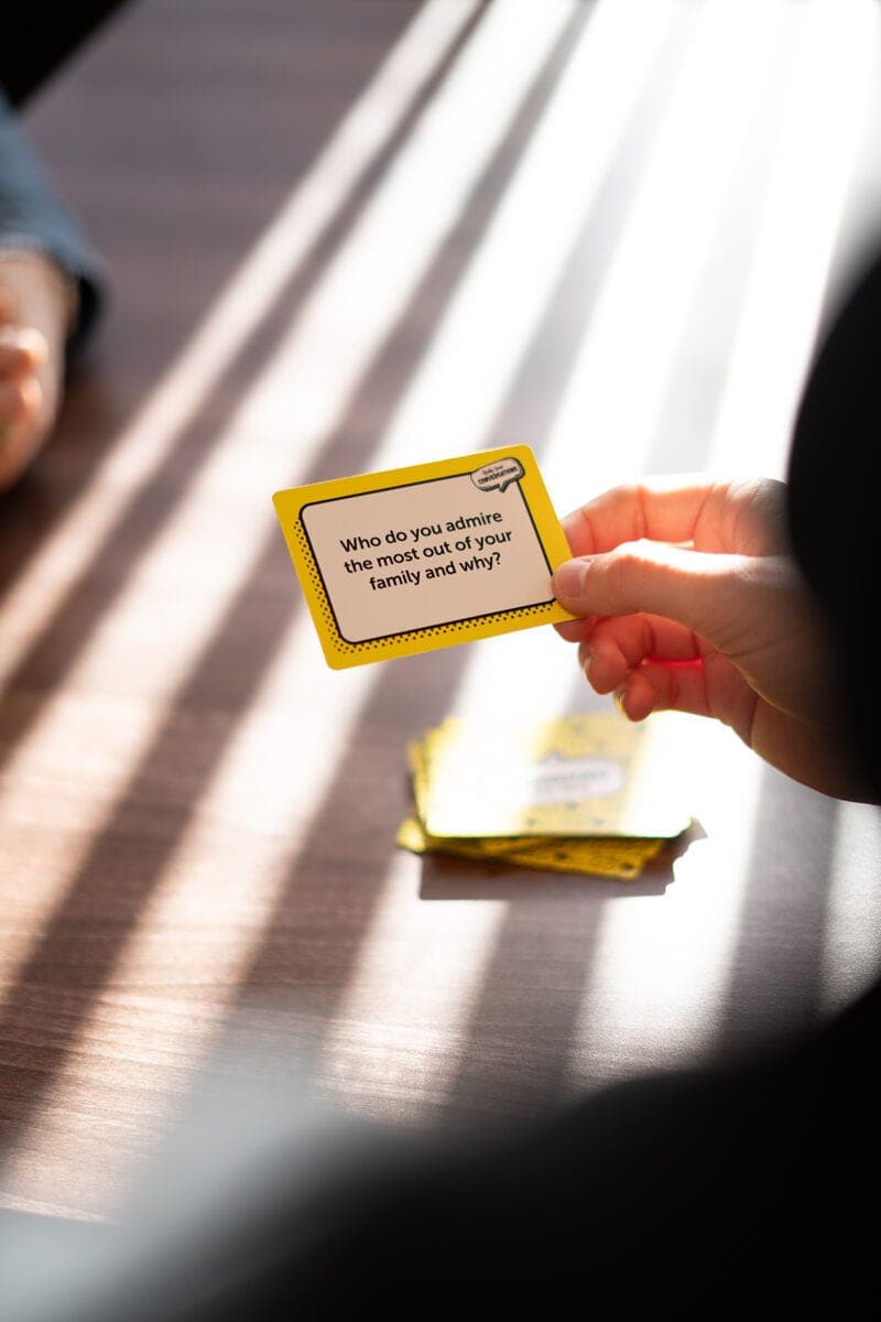 Hand holding a Really Good Conversations card in sunlight